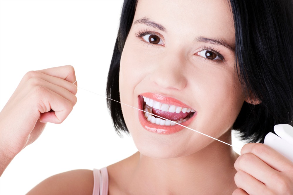 Beautiful young woman using dental floss